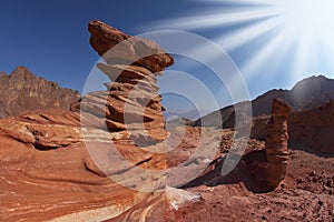 The sparkling sun above interesting natural forms of sandstone hoodoos