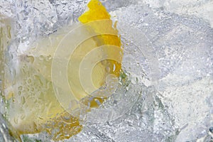 Sparkling water with lemons and ice cubes in glass close up