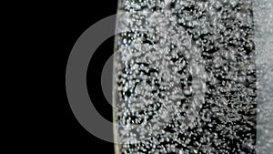Sparkling of white wine. White wine being poured into a glass of black background. Fragolino