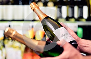 Sparkling wine in alcohol store. Champagne or prosecco in liquor shop. Man holding two bottles in hands, choosing drink.