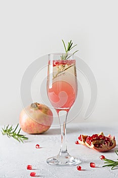 Sparkling wine, pomegranate, rosemary sprig on white table. Xmas drink
