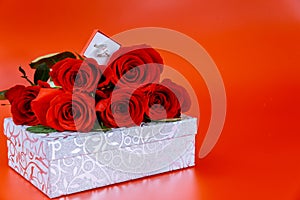 Sparkly gift box and ring with beautiful red roses on red background. Valentines Day