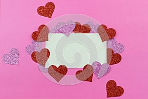Sparkly pink and red hearts surround a parchment paper tage on a bright pink background for Valentine`s Day in February. Copy spa photo
