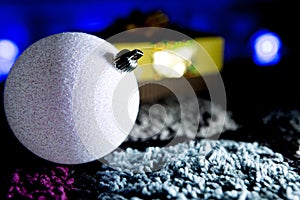 Sparkly White Christmas Ball with Gift in Colorful Background