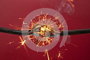 Sparks explosion between electrical cables, on red  background, fire hazard concept, soft focus close up