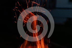 Sparks and flame erupt from the top of a chimney starter fire on a backyard grill