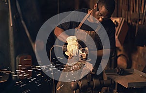 Sparks fly in the heat of the moment. a young man using an angle grinder while working at a foundry.