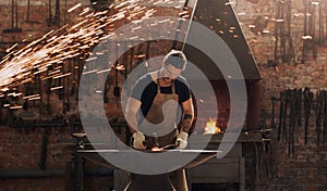 Sparks fly when I do what I love most. a metal worker hitting a hot metal rod with a hammer in a welding workshop.