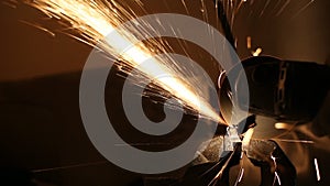 Sparks fly while the man cutting a metal rod with a grinding machine
