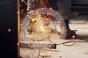 Sparks flying. Close up view of man`s legs and hands with slicing tool. Working with metal