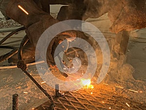 Sparks from a welding torch during the work of the welder. The master solders a metal rod with a tool. Worker cuts reinforced