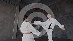 Sparring or single duels in taekwondo school. Pupils stand in a fighting stance and carry out huge kicks. Forceful