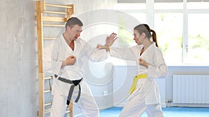 Sparring woman and man in white kimono during karate training in the gym