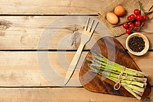 Sparrow grass. Fresh Green Asparagus with eggs and pepper on wooden board. Top view photo