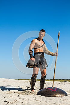 Spartan winner stands majestically with a spear and helmet in his hands
