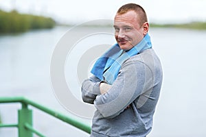 Sparty active man resting after workout with towel on shoulders.