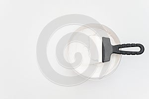 Spatula and a bucket of putty on white wooden boards. Top view Copy space photo