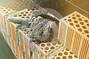 Spatula and cement mortar, red brick masonry, construction concept