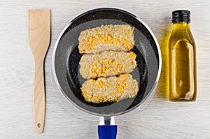 Spatula, raw cutlets in frying pan, bottle of vegetable oil