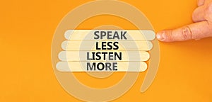 Speak less listen more symbol. Concept words Speak less listen more on wooden stick. Beautiful orange table orange background.