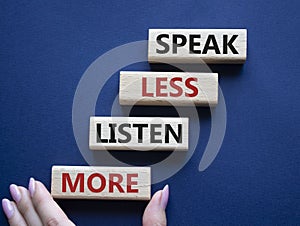 Speak less Listen more symbol. Wooden blocks with words Speak less Listen more. Beautiful deep blue background. Businessman hand.