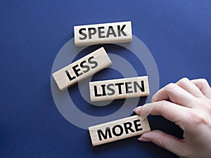 Speak less Listen more symbol. Wooden blocks with words Speak less Listen more. Beautiful deep blue background. Businessman hand.