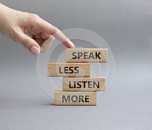 Speak less Listen more symbol. Wooden blocks with words Speak less Listen more. Beautiful grey background. Businessman hand.