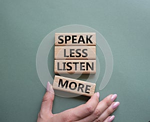 Speak less Listen more symbol. Wooden blocks with words Speak less Listen more. Beautiful grey green background. Businessman hand
