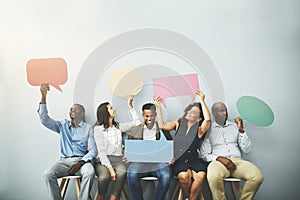Speak up and have your say. Studio shot of a group of businesspeople holding colorful speech bubbles in line against a
