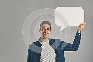 Speak your mind. Studio portrait of a young man holding a speech bubble against a grey background.