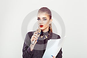 Speaker. A business woman speaking at the microphone looking at you camera and holding the papers. Presentation speech concept