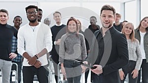 Speaker and a group of young listeners standing in a conference room.