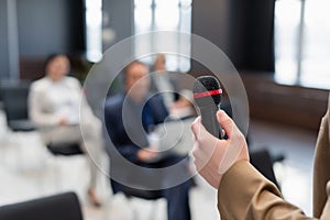 speaker holding microphone near blurred participants