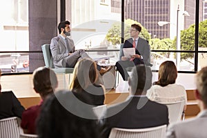 Speaker and interviewer in front of audience at a seminar