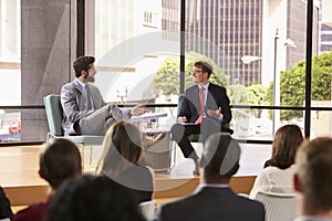 Speaker and interviewer talk in front of audience at seminar