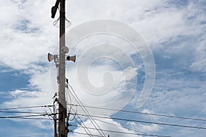 Speakers on electric pole with a blue sky background