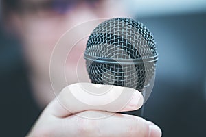 Speaking in the microphone: Young man with blurry face is taking into the microphone