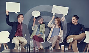 Speaking our business minds. a group of businesspeople holding up speech bubbles while waiting in line for an interview.