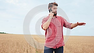 Speaking on phone charismatic man farmer while walking through the wheat field he gesticulating with hand in front of