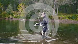 Spear fisherman shows Freshwater Fish at after hunting in forest river