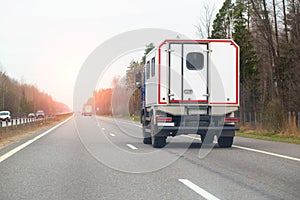 A special cargo vehicle with the body of a mobile repair workshop is driving along a country road against the backdrop