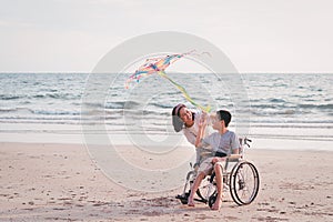 Special child on wheelchair is fun, playing and exercise activity on sea beach at summer