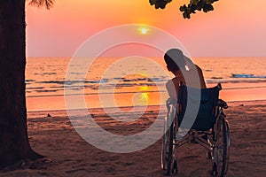 Special child on wheelchair on the sea beach with sunset on travel time