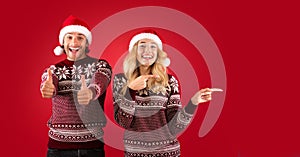 Special Christmas offer. Young guy showing thumbs up while his girlfriend pointing at blank space, red background