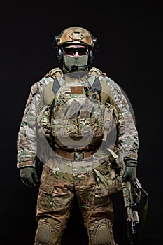 Special forces soldier man in military gear, protective mask, glasses and mask hiding his face with machine gun is