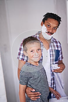 Special moments like these always brings smiles. Portrait of a father and son shaving together in a bathroom.