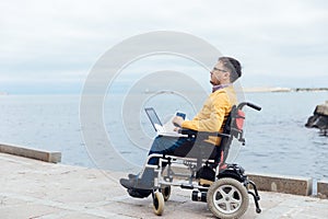 a special person with disabilities by the sea with a laptop