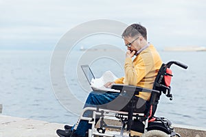 a special person with disabilities by the sea with a laptop