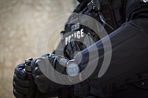 A special police officer holds a pistol, a sword and a grenade in his hands