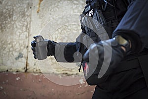 A special police officer holds a pistol, a sword and a grenade in his hands